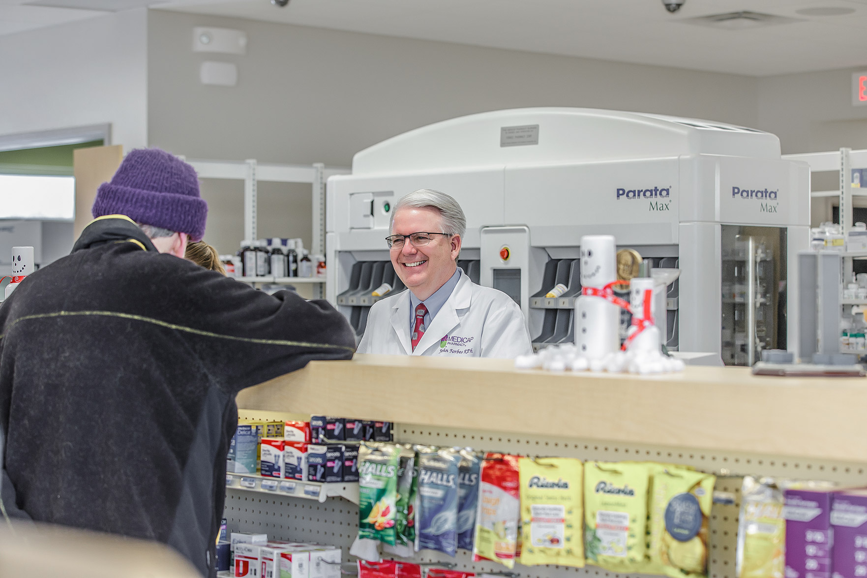 John Forbes with a customer at Medicap Pharmacy
