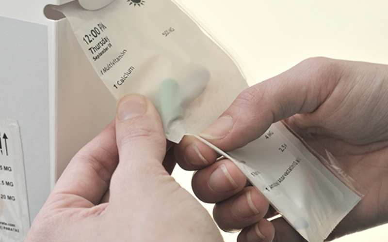 Patient removing a pack from a medication strip