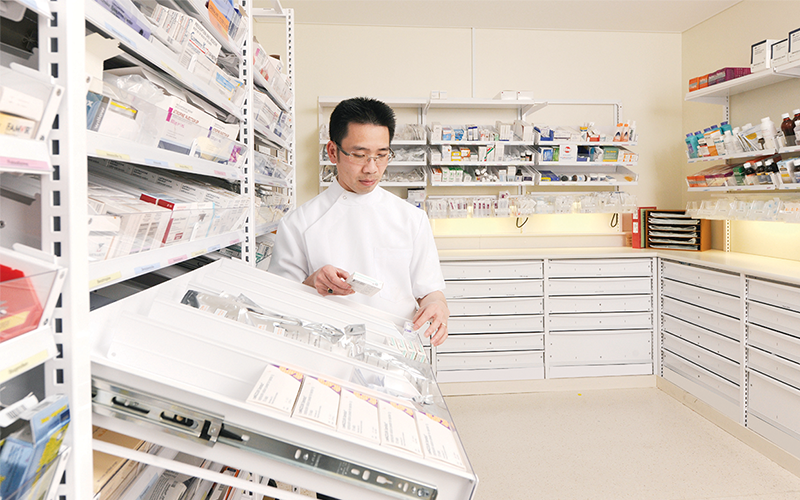 Pharmacist reviewing prescription medication inventory in an automated pharmacy dispensing system