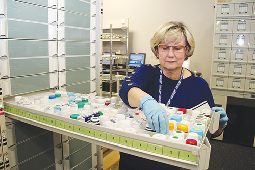 Technician picking up Rx bottle from Beacon cabinet